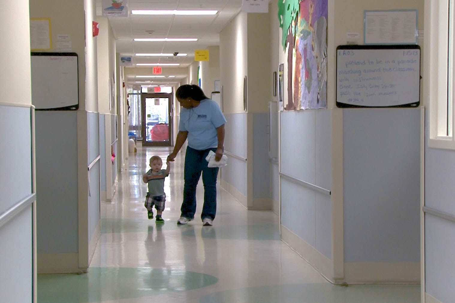 a staff member assists a child down a hallway