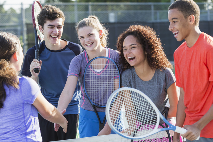 A group of teens playing tennis