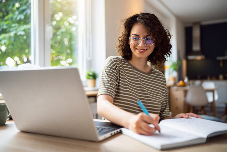 a woman sits at a desk working on a laptop