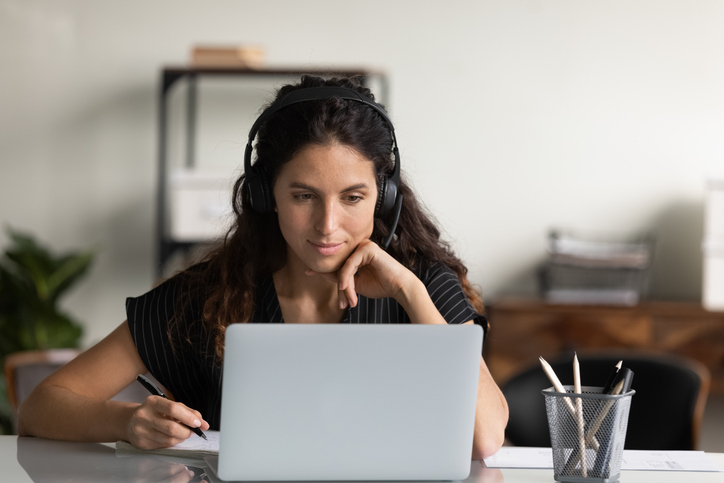A woman wearing headphones working in front of a laptop