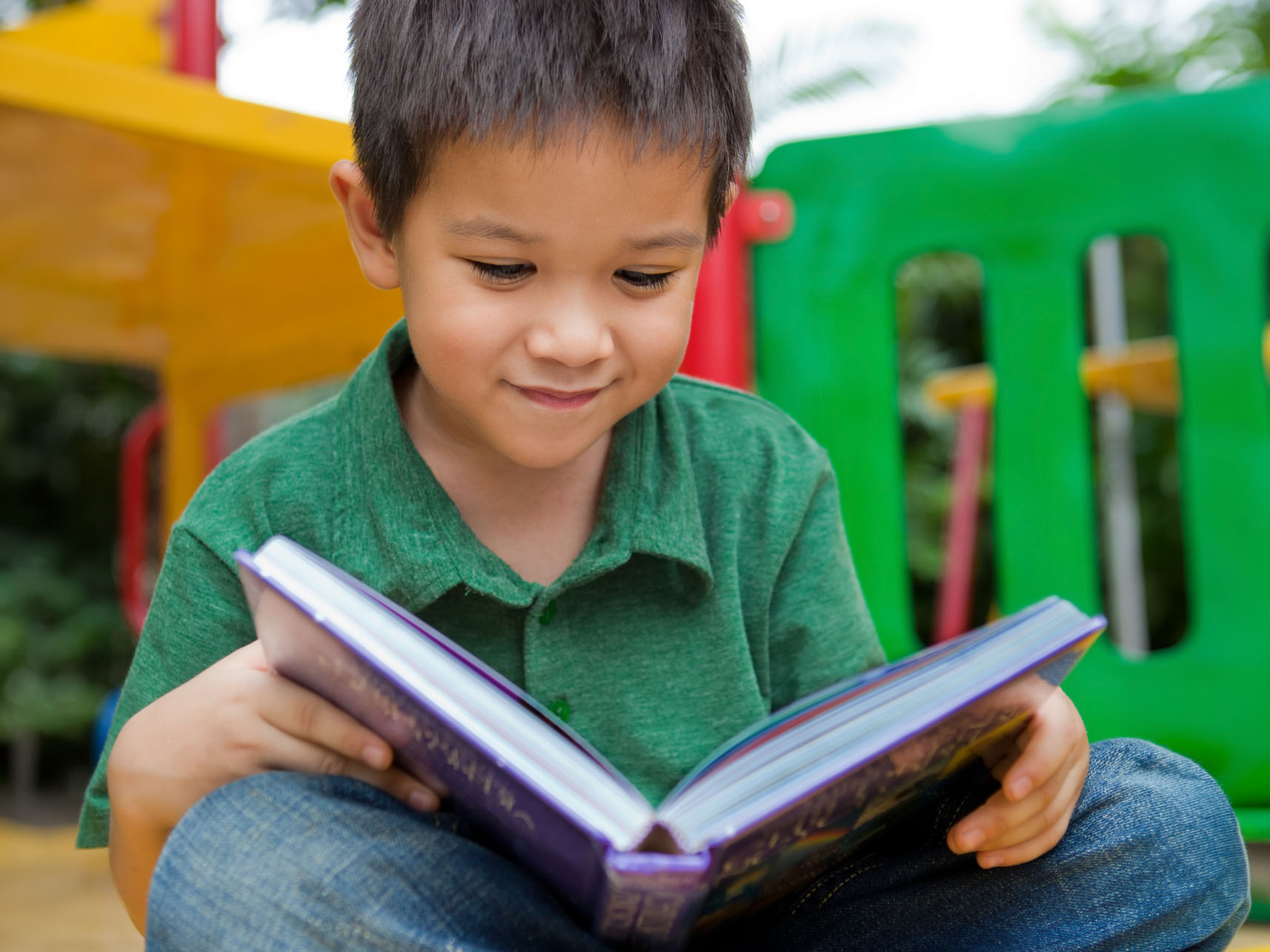 a boy reading by the playground