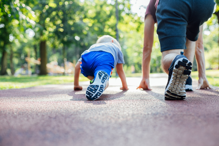 a child and an adult get in ready stance to start a play-race at a playground